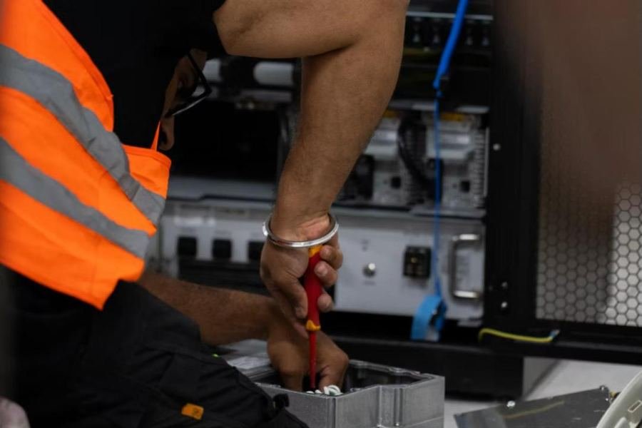 Technician in a high-visibility vest installing network equipment